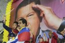 Venezuela's acting President Maduro carries child in front of poster of late president Chavez during campaign rally in Lara