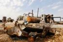 Men walk among debris at an oil refinery and a gas station that were targeted by what activists said were U.S.-led air strikes, in Tel Abyad