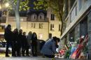 People pay their respects under a commemorative plaque next to the "La Belle Equipe" bar and restaurant in Paris