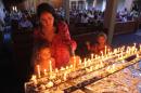 A mother and her children light candles during a church service in honour of Nelson Mandela in Johannesburg, South Africa, Sunday, Dec. 8, 2013. People in South Africa are taking part in a day of "prayer and reflection" for late President Nelson Mandela. (AP Photo/Tsvangirayi Mukwazhi)