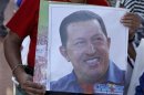A supporter of Venezuelan President Chavez holds a picture of him, as he attends a mass to pray for Chavez's health in Caracas