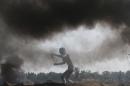 Palestinian protester uses a sling to hurl stones at Israeli troops during clashes near border between Israel and Central Gaza Strip