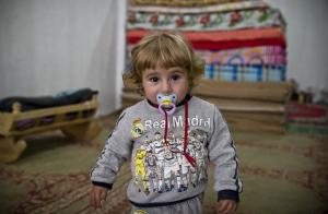 A Syrian Kurdish refugee child from Kobani stands in …