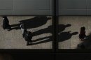 Office workers are reflected on a building as they cast their shadows during lunch time in central
