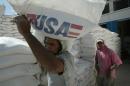 Iraqi workers haul sacks of flour donated by the United States in the Sadr City locality of Baghdad on September 11, 2003