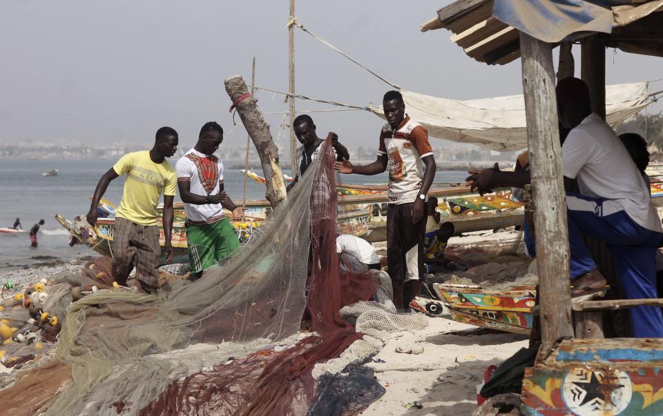 In this photo taken on Monday, June 15, 2015, fishermen repair their fishing nets as part of preparation to go out at sea in Thiaroye, Senegal...