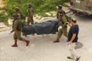 Israeli soldiers remove the body of a Palestinian assailant who was allegedly shot in head by an Israeli soldier, in the West Bank town of Hebron on March 24, 2016