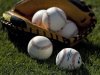 Baseballs and a catcher's mitt lie on the grass before a MLB spring training baseball game between the Red Sox and Orioles in Sarasota
