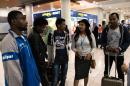 A volunteer (2R) talks to four African refugees after they arrived at Larnaca International airport from Italy on May 17, 2016 as part of an EU relocation programme