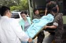 A wounded South Korean soldier who killed five comrades in a shooting incident on a stretcher is carried from an ambulance upon arrival at a hospital in Gangneung, South Korea, Monday, June 23, 2014. The South Korean army captured the soldier Monday who it says killed five comrades and then fled into the forest where he holed up with a rifle for two days before shooting himself as pursuers closed in. The massive manhunt ended when the 22-year-old sergeant, surnamed Yim, shot himself in the upper left chest as his father and brother approached, pleading with him to surrender, a Defense Ministry official said. (AP Photo/Yonhap, Lee Sang-hack) KOREA OUT