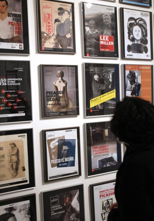 Una visitante contempla un grupo de carteles expuestos en el Museo Picasso que plantea en una muestra un viaje por las 79 exposiciones temporales que han difundido la obra del pintor malagueño en los 
