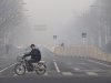 FILE - In this Jan. 10, 2012 file photo, a man rides an electric bike crossing a street shrouded by haze in Beijing. A senior Chinese environmental official told foreign embassies on Tuesday, June 5, 2012 to stop publishing their own reports on air quality in China, a clear reference to a popular U.S. Embassy Twitter feed that tracks pollution in smoggy Beijing. (AP Photo/Andy Wong, File)