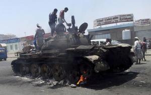 People stand on a tank that was burnt during clashes &hellip;