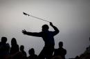FILE - In this Friday, Nov. 21, 2014 file photo, a Palestinian protester using a sling shot throws a stone towards Israeli security forces during clashes following a protest against Israeli restrictions on the Al-Aqsa Mosque in Jerusalem, at the Qalandia checkpoint near the West Bank city of Ramallah.(AP Photo/Majdi Mohammed, File)
