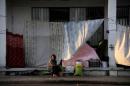 A woman sits and looks on outside a building covered up with sheets to protect the dwellers from the strong summer sun outside of the disused Hellenikon airport, where stranded refugees and migrants are temporarily accommodated in Athens