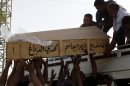 Family members of Bilal Aziz, 20, who was killed in a car bomb attack load his coffin onto a vehicle before burial in Najaf, 100 miles (160 kilometers) south of Baghdad, Iraq, Wednesday, June 13, 2012. A wave of bombings targeted religious processions during the annual pilgrimage commemorating the 8th century death of a revered Shiite imam, killing and wounding scores of people, police said. (AP Photo/Alaa al-Marjani)