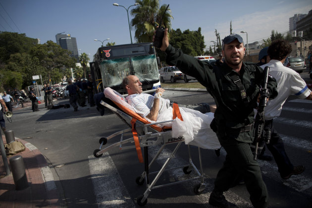 Israeli rescue workers and paramedics carry a wounded person from the site of a bombing in Tel Aviv, Israel, Wednesday, Nov. 21, 2012. A bomb ripped through an Israeli bus near the nation's military headquarters in Tel Aviv on Wednesday, wounding several people, Israeli officials said. The blast came amid a weeklong Israeli offensive against Palestinian militants in Gaza that has killed more than 130 Palestinians. (AP Photo/Oded Balilty)