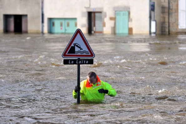 أحد رجال الحماية المدنية يحاول الامساك بإشارة طريق وسط الفيضانات التي اجتاحت فرنسا هذا الأسبوع والإشارة تحمل علامة تحذر من خطر الإنزلاق