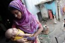 Rabeya holds her one-month old daughter Sumaiya in front of her slum house at Hatirjheel in Dhaka