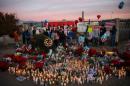 People gather at a makeshift memorial near the Inland Regional Center during the aftermath of a mass shooting that killed 14 people on Sunday, December 6, 2015 in San Bernardino, California