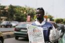 A man sells newspapers, featuring a front page article about Nigerian soldiers rescuing a group of women, in Abuja