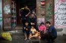 A Palestinian family warm themselves by a a fire next their shop on a rainy day in Al-Shati refugee camp in Gaza City on December 11, 2013