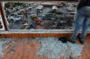 A man stands on shattered glass overlooking a damaged bus station after explosions hit it in the Syrian city of Jableh