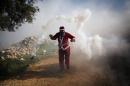 A Palestinian protester wearing a Santa Claus costume uses a sling to throw back a tear gas canister fired by Israeli soldiers during a protest against Israel's separation barrier outside the West Bank village of Bilin, near Ramallah, Friday, Dec. 26, 2014. (AP Photo/Majdi Mohammed)