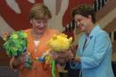 German Chancellor Angela Merkel, left, is gifted a plush version of the Rio 2016 Olympic mascot Vinicius, in yellow, and a plush version of the Paralympic mascot Tom, during lunch at the Itamaraty Palace, in Brasilia, Brazil, Thursday, Aug. 20, 2015. Merkel made a two-day stop to boost ties with Brazil. She also plans to meet with German business representatives before heading back home on Thursday. (AP Photo/Eraldo Peres)
