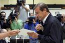 Portuguese Prime Minister Pedro Passos Coelho picks up his ballot to vote in Portugal's general elections Sunday, Oct. 4 2015, in Massama, outside Lisbon. The last polls ahead of Sunday's election showed the center-right ruling coalition roughly level with the center-left Socialist Party, the main opposition. (AP Photo/Armando Franca)