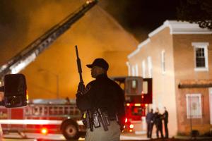 An officer stands near a blaze, Monday, April 27, 2015, …