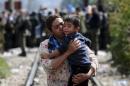 A woman carries a boy after crossing Greece's border into Macedonia near Gevgelija, Macedonia