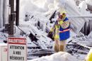 An emergency worker walks past a sign that reads "Look out for our residents" as they search through the icy rubble of a fire that destroyed a seniors' residence Friday, Jan. 24, 2014, in L'Isle-Verte, Quebec. Five people are confirmed dead and 30 people are still missing, while with cause of Thursday morning's blaze is unclear police said. Authorities are using steam to melt the ice and to preserve any bodies that are buried. (AP Photo/The Canadian Press, Ryan Remiorz)