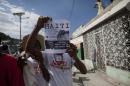 A demonstrator holds up a leaflet that shows an image of former president Bill Clinton, asking where the aid money for reconstruction went, in Port-au-Prince, Haiti, Saturday, Jan. 10, 2015, during a protest calling for the resignation of Haiti's President Michel Martelly. Recovery from the the Jan. 12 2010, 7.0 earthquake has been uneven, plagued by poor planning and accusations of graft. Many poor Haitians say their lives have been complicated by a rising cost of living and lack of jobs, and they put the blame squarely on the government for failing to create opportunities. ( AP Photo/Dieu Nalio Chery)