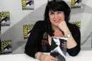 FILE - In this July 12, 2012, file photo, author E.L. James poses with her book "Fifty Shades of Grey" at a book signing at Comic-Con in San Diego. The top 10 list of "challenged" books at public schools and libraries, released Monday, April 11, 2016, by the American Library Association includes James' best-selling book. (Photo by Denis Poroy/Invision/AP, File)