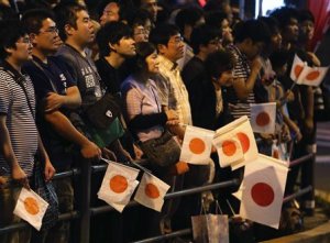 People holding Japanese national flags listen to Japan's …
