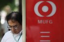 A man walks past next to a sign board bearing the logo of the Mitsubishi UFJ Financial Group outside its branch in Tokyo