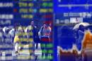 People are reflected on an electronic stock indicator of a securities firm in Tokyo, Monday, June 29, 2015. Tokyo stocks plunged more than two percent in early trading on Monday as fears mounted over Greece's debt crisis after eleventh-hour talks collapsed. (AP Photo/Shizuo Kambayashi)