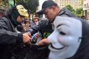 Policemen look into the backpack of a man wearing a Guy Fawkes mask in Rio de Janeiro, Brazil on November 5, 2013