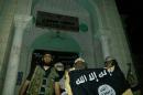 A picture taken with a mobile phone early on May 24, 2014 shows Al-Qaeda militants posing with the Al-Qaeda flag in front of a museum in Seiyun, second Yemeni city of Hadramawt province