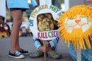 Girl holds sign at the doorway of Bloomington's River Bluff Dental clinic in protest against the killing of a famous lion in Zimbabwe