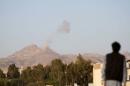 Man looks on as smoke billows from military barracks in the Jabal al-Jumaima mountain following an air strike near Sanaa