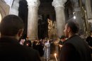 Christian clergymen hold candles inside the Church of the Holy Sepulchre, in Jerusalem's Old City, Friday, Nov. 2, 2012. A clergyman from the church built on the site where Jesus Christ is said to have been crucified said Friday that its bank account has been frozen as the result of a long-standing dispute with an Israeli water company. (AP Photo/Sebastian Scheiner)