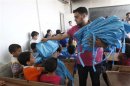 A man distributes bags donated from UNICEF to young students in Raqqa
