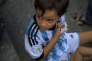 A child wearing the team jersey of Argentina holds photos of soccer players he needs to get, to complete his World Cup sticker album, at a meeting of collectors in Caracas, Venezuela, Saturday, June 21, 2014. While soccer has long taken a backseat to baseball and even basketball in Venezuela, the ritual of sicker collection still sparks a frenzy. Politicians, TV personalities, and professional collectors can all be found at ad-hoc trading centers, searching for the more than 600 stickers that constitute a complete 2014 collection. (AP Photo/Ramon Espinosa)