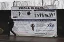A man walks by a sign that reads "Ebola is real" in Monrovia