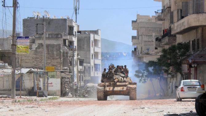 Armed rebel fighters drive a tank in the northern town of Jisr al-Shughur on April 26, 2015