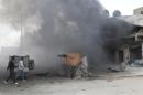 Men walk at a site hit by what activists said were barrel bombs dropped by forces loyal to Syria's President Bashar al-Assad in Aleppo's al-Sakhour district