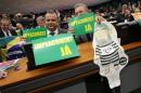Opposition deputies hold an inflatable doll in the likeness of former President Luiz Inacio Lula da Silva in prison garb and the signs that read in Portuguese "Impeachment Now," during a meeting of the Parliamentary Commission which examines the request for the impeachment of Brazil's President Dilma Rousseff, in Brasilia, Brazil , Monday, April 11, 2016. The special investigator of the impeachment commission in the lower house of Brazil's Congress Jovair Arantes, recommended that the impeachment process against President Rousseff move forward. (AP Photo/Eraldo Peres)