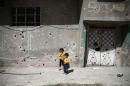 Children stand in front of the bullet-riddled facade of a building in the rebel-held Douma neighbourhood of Damascus